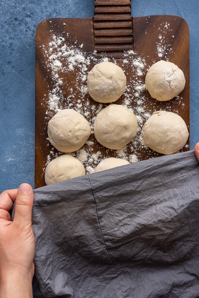 Woman covering lahmacun dough balls with a piece of damp cloth.