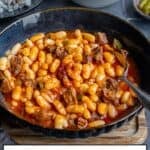 Turkish kuru fasulye bean stew with tender beef in a rich tomato sauce, served with rice pilaf, cacik, and pickles.