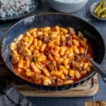 Turkish bean stew in a dark colored bowl and a spoon inside it.