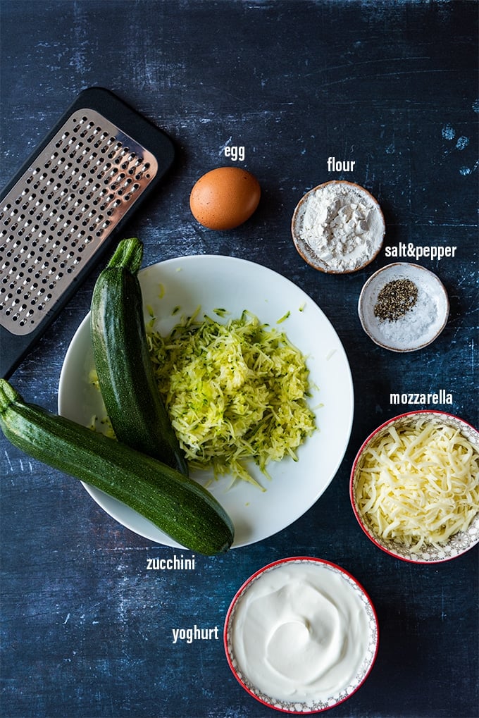 Zucchini cheese casserole ingredients on a dark background.