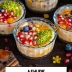 Ashure dessert in glass bowls, garnished with pomegranate seeds, ground pistachio and blueberries.