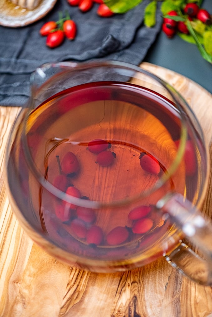 Rosehip tea in a glass pot on a wooden board