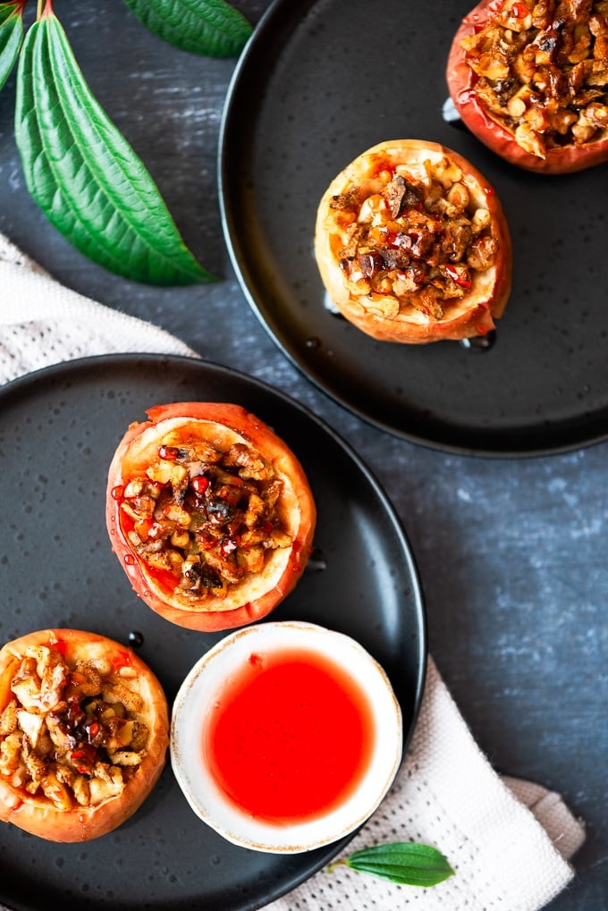 Stuffed baked apples and beet syrup served on black plates.