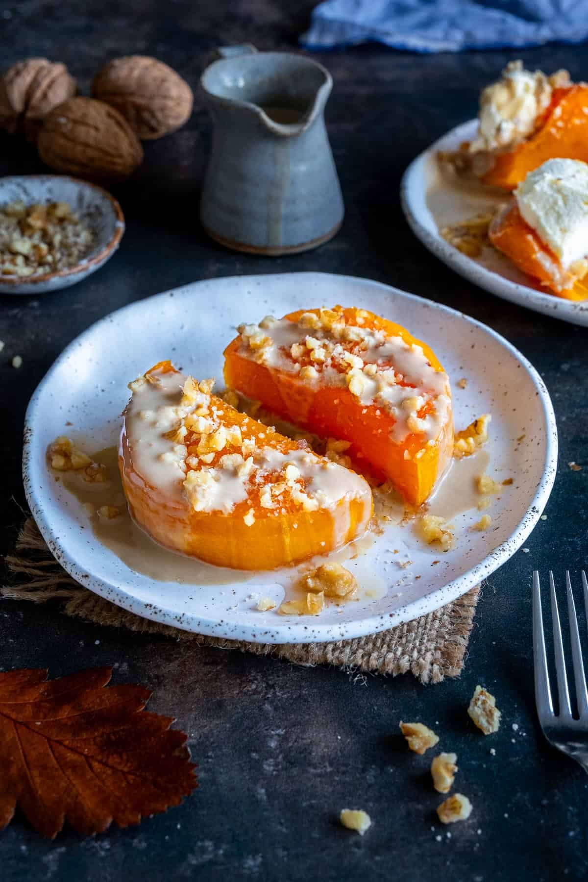 Turkish Pumpkin Dessert (Kabak Tatlısı) served on a white plate, topped with tahini and chopped walnuts, with syrup drizzled over the soft baked pumpkin pieces.