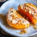 Close-up of Turkish Pumpkin Dessert (Kabak Tatlısı) topped with tahini and chopped walnuts, served on a white plate with syrup.