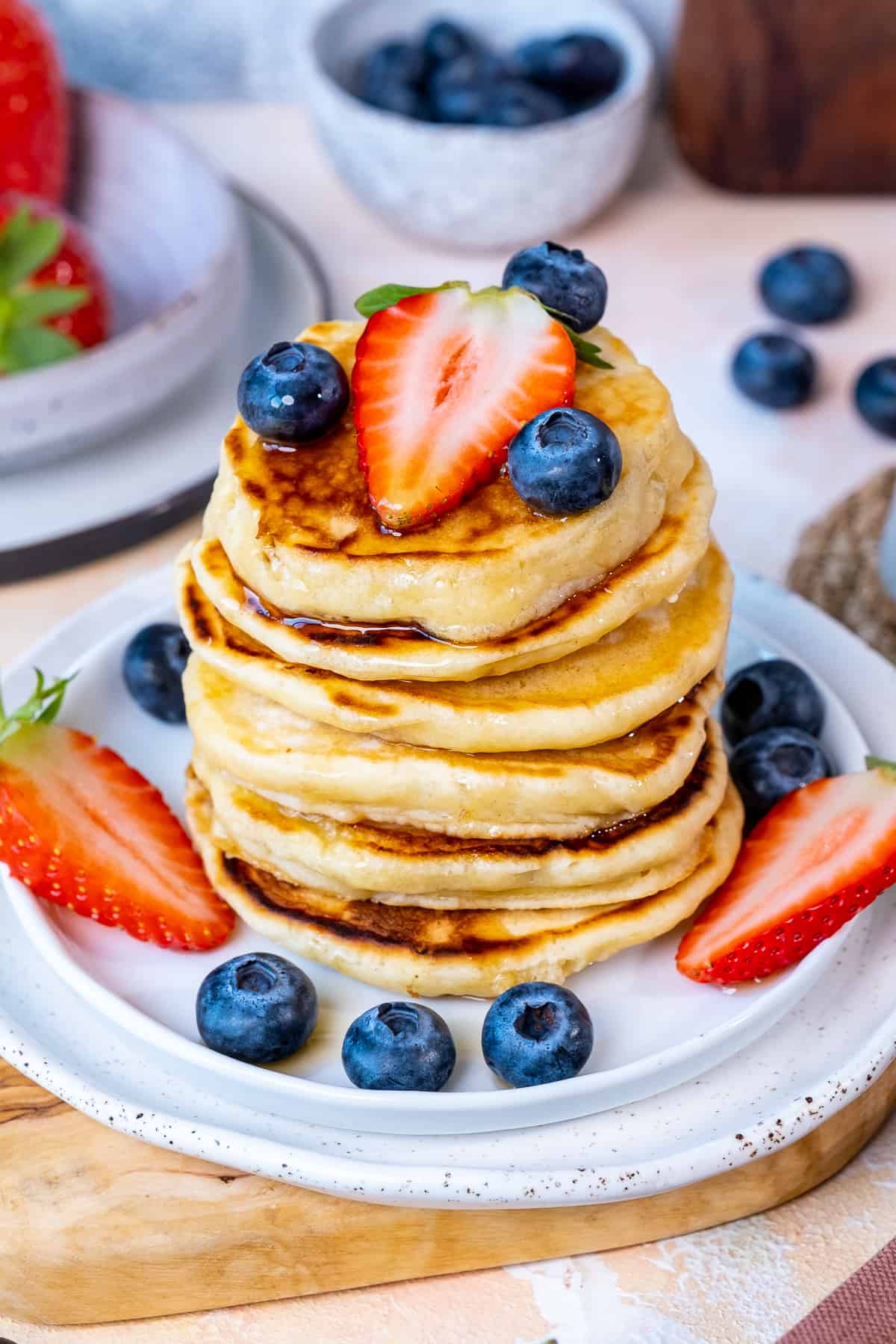 Almond milk pancakes served with blueberries and strawberries on a white plate.