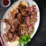 Doner kebap served with sumac onions and parsley on an oval plate.