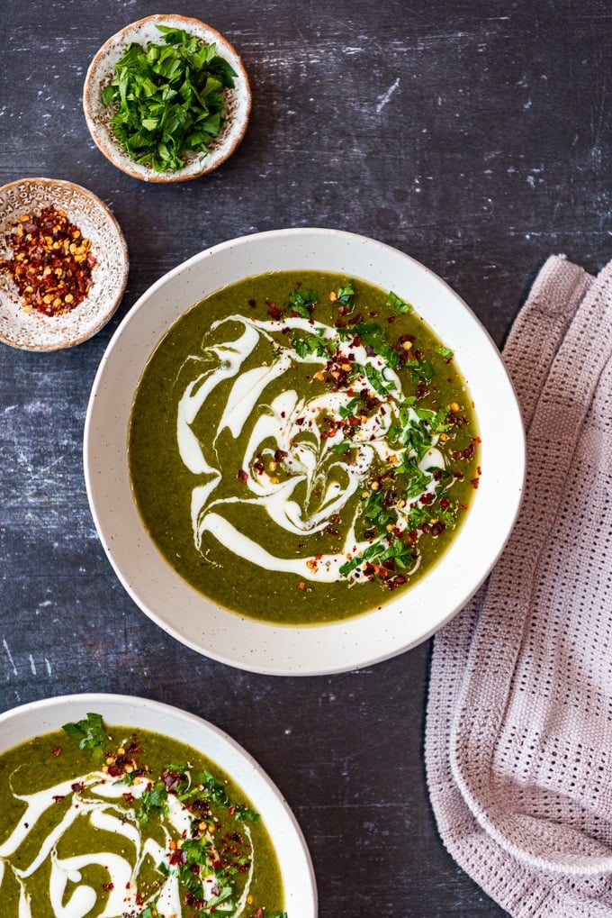 Creamy green soup with spinach and lentils with coconut cream topping in two bowls