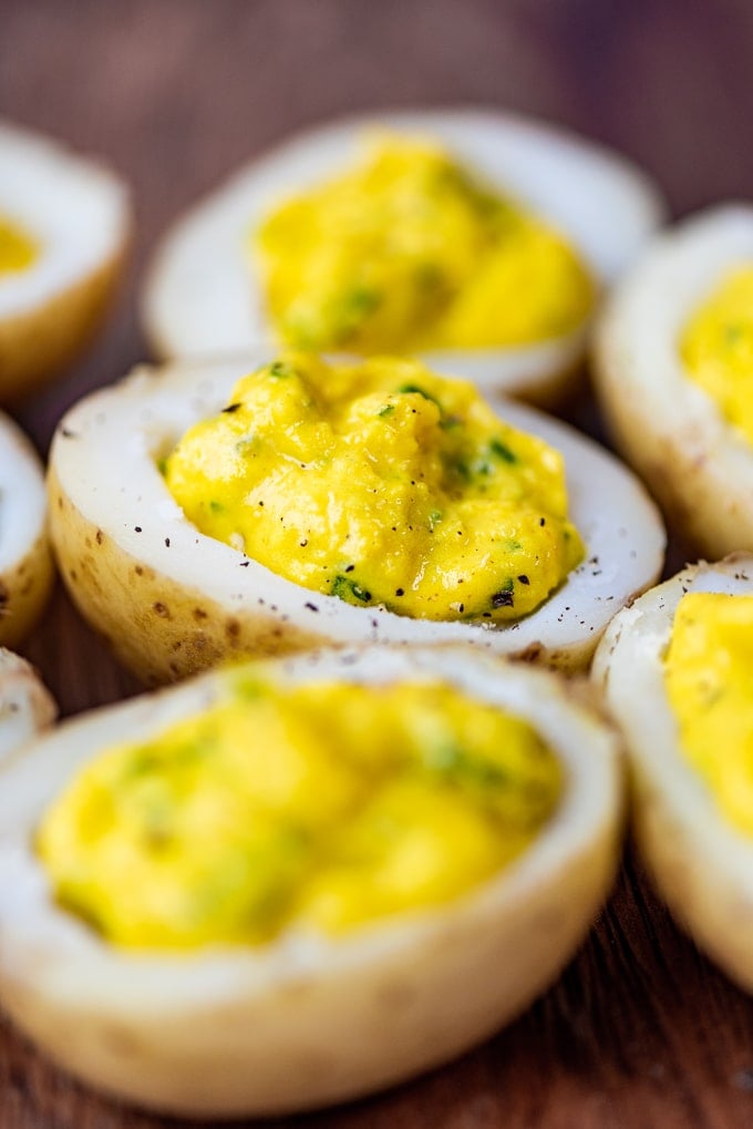 Potato deviled eggs as a vegan finger food on a wooden board