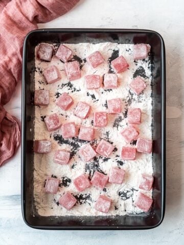 Turkish Delight lokum cubes coated with cornstarch and powdered sugar in a black rectangular pan