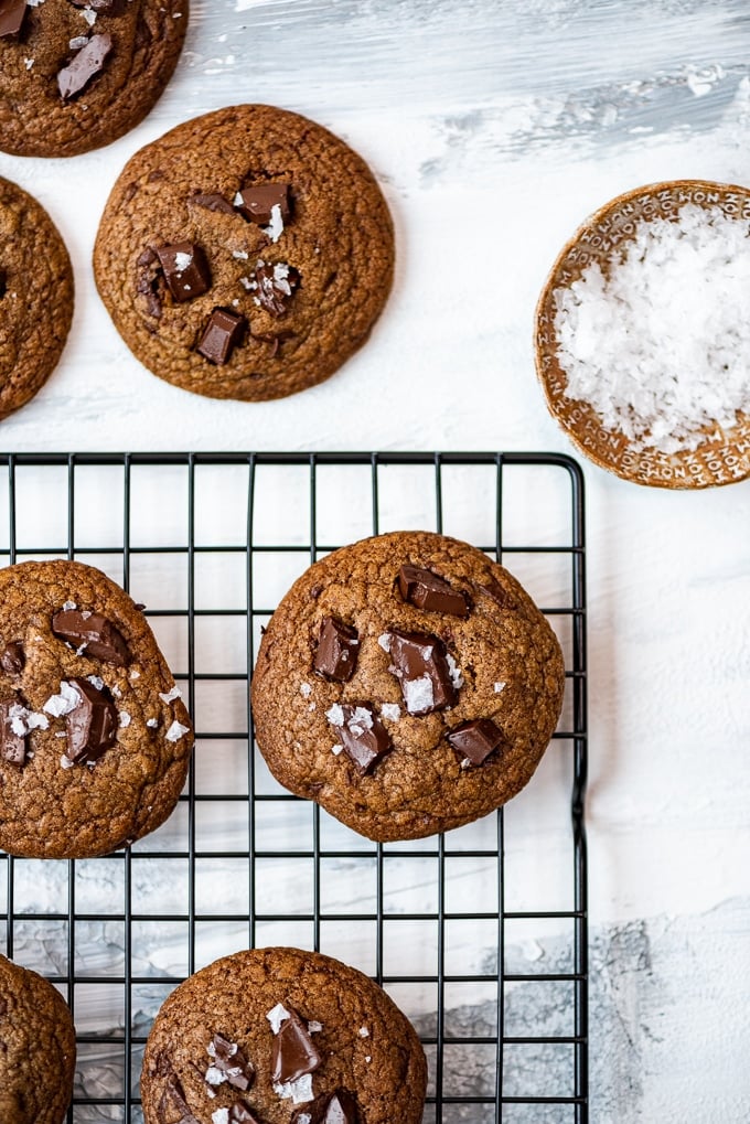 Turkish cofee flavored cookies on a cooling rack accompanied by a small bowl of flaky salt
