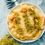 Turkish halva made with flour and syrup served on a white plate with ground pistachio.