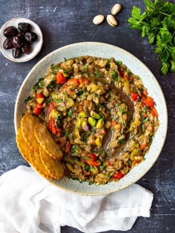 Chunky no tahini baba ganoush with peppers in a bowl with crackers on the side.