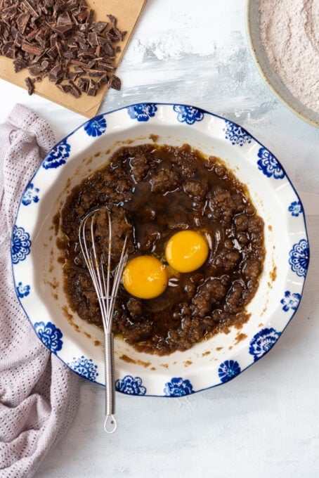 making brown butter cookie dough in a mixing bowl with eggs and a whisk