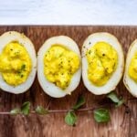 Vegan deviled eggs made with potatoes on a wooden board.