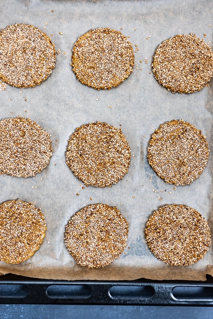 Tahini cookies coated well with sesame seeds on a baking sheet.