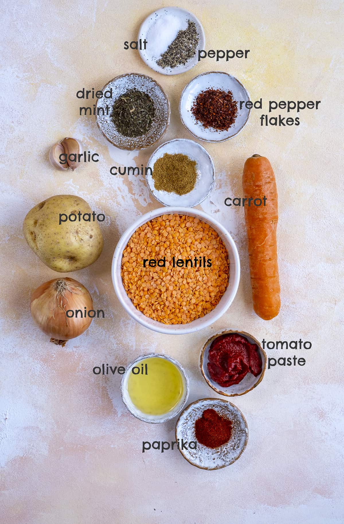 Red lentils, vegetables, spices and oil on a light background.