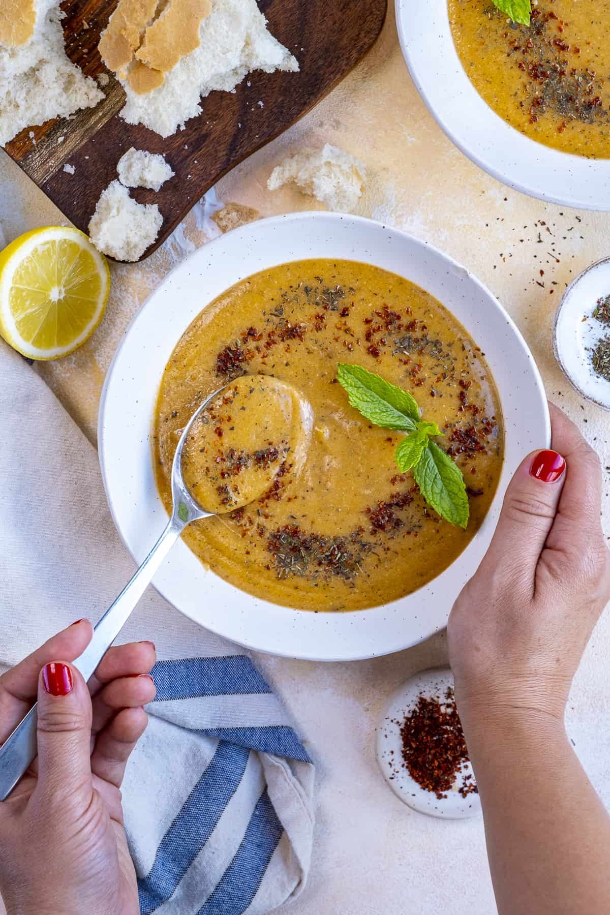 Woman holding a bowl of lentil soup and a spoon in one hand.