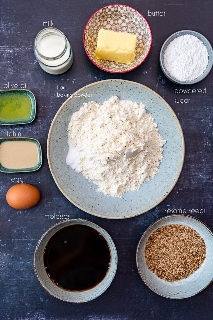 Sesame seed cookie recipe ingredients in separate bowls on a dark background.