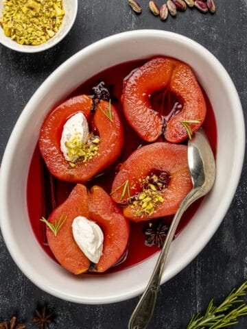 Turkish quince dessert garnished with clotted cream and ground pistachio in a white oval bowl.