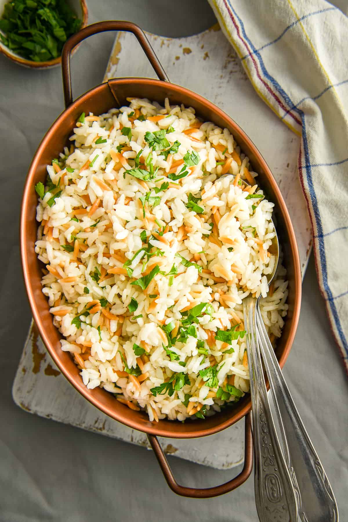 Rice with orzo in an oval pan and two spoons inside it.