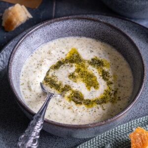 Close-up of a bowl of Turkish Yogurt Soup (Yayla Çorbası) topped with butter-mint sauce, served with bread on the side.
