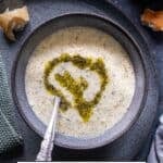 A bowl of Turkish Yogurt Soup (Yayla Çorbası) topped with butter-mint sauce, served with crusty bread on the side.