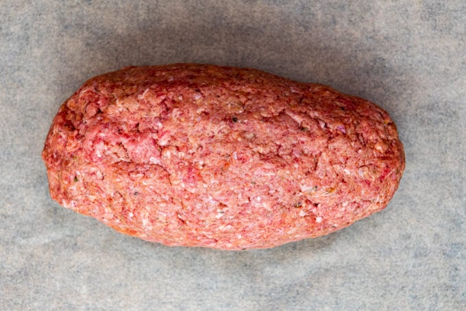 A log of ground beef mixture on a piece of baking paper.