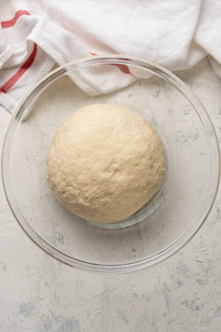 Leavened dough in a glass mixing bowl.