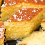 Close-up of revani (Turkish semolina cake) slices, golden and syrup-soaked with a soft crumb, topped with desiccated coconut.