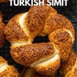 Close shot of a simit bread with a golden color coated with sesame seeds on a dark background.