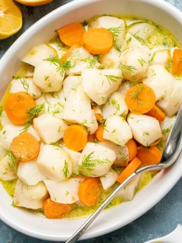 Braised Jerusalem artichokes and carrots in a white oval bowl.