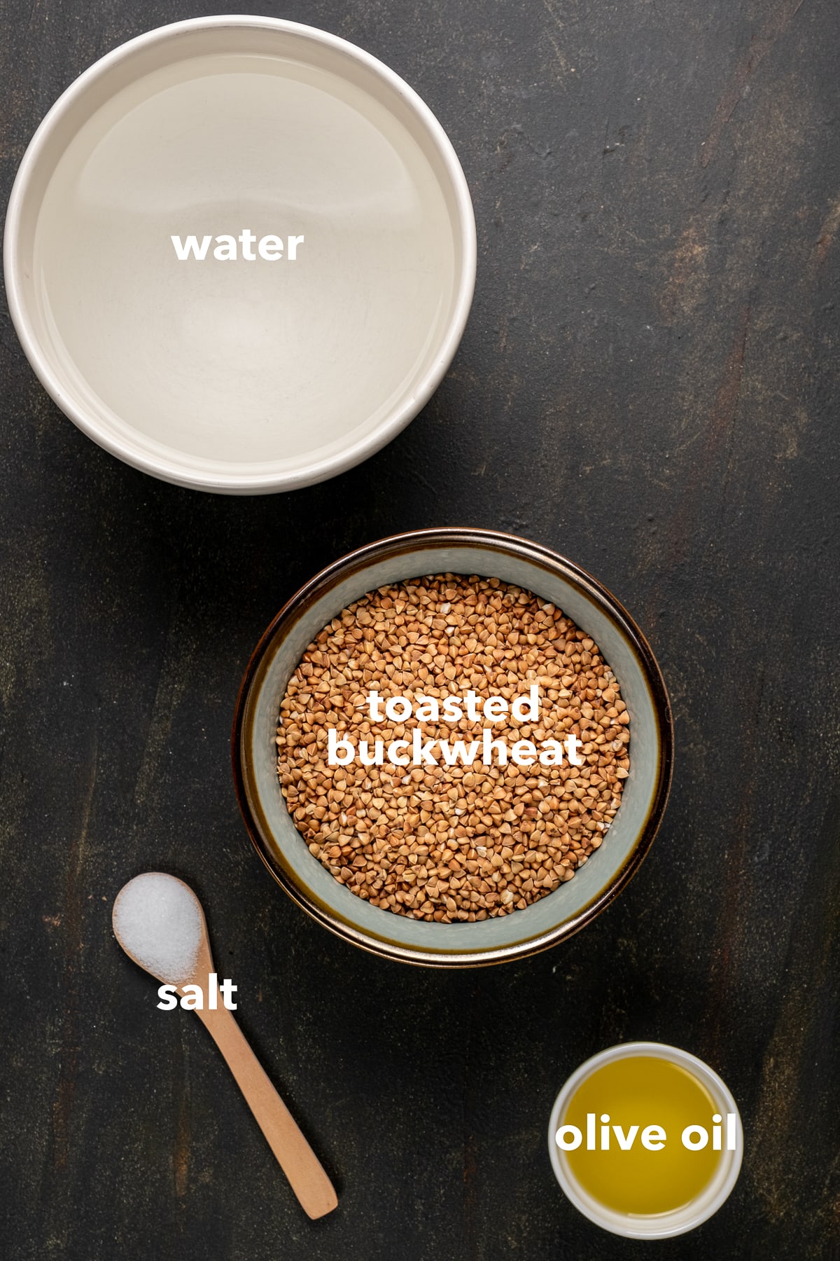 Toasted buckwheat, water, olive oil in bowls and salt in a small wooden spoon