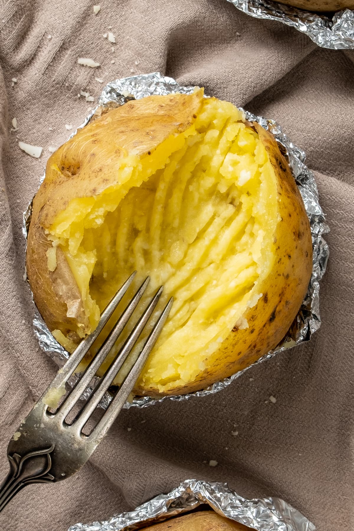 Butter and cheese fully mixed in the baked potato until creamy and a fork inside it.