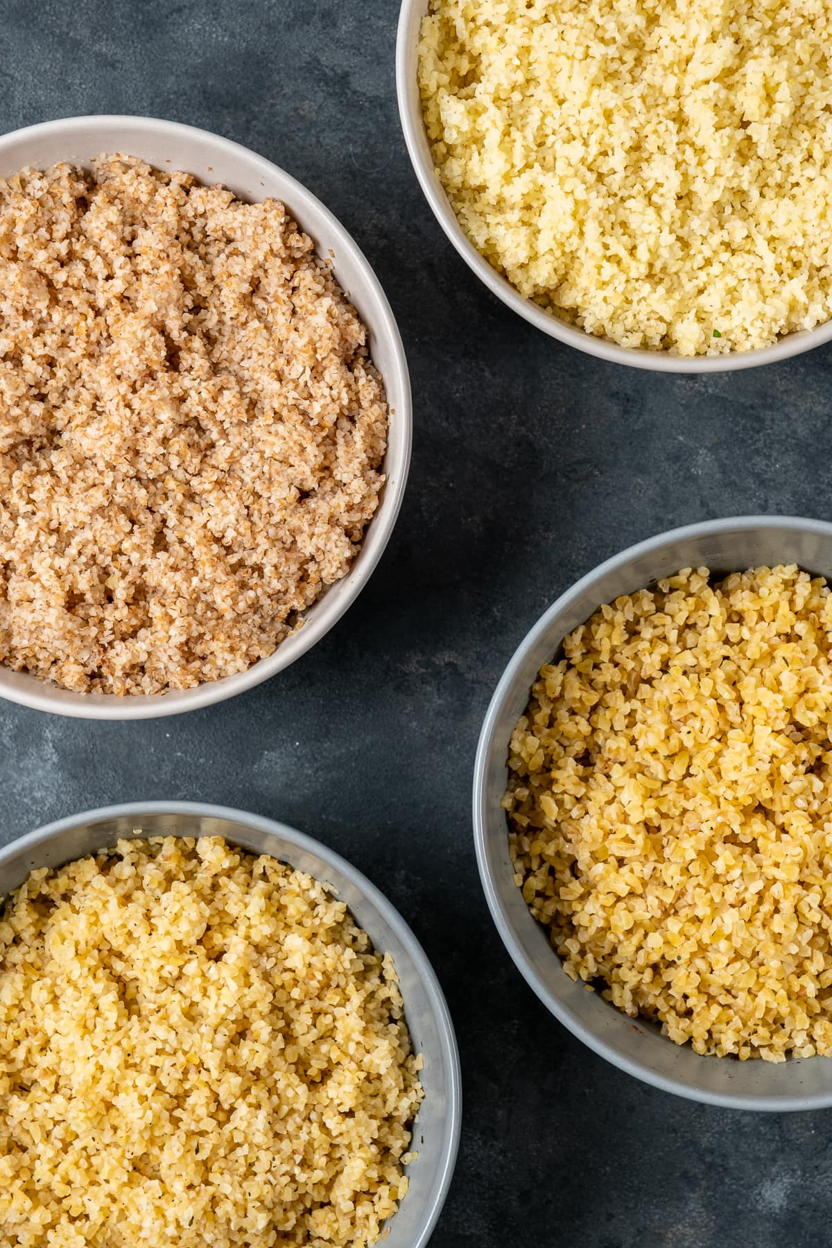 Fine bulgur and medium bulgur after soaked in four different bowls on a dark background.