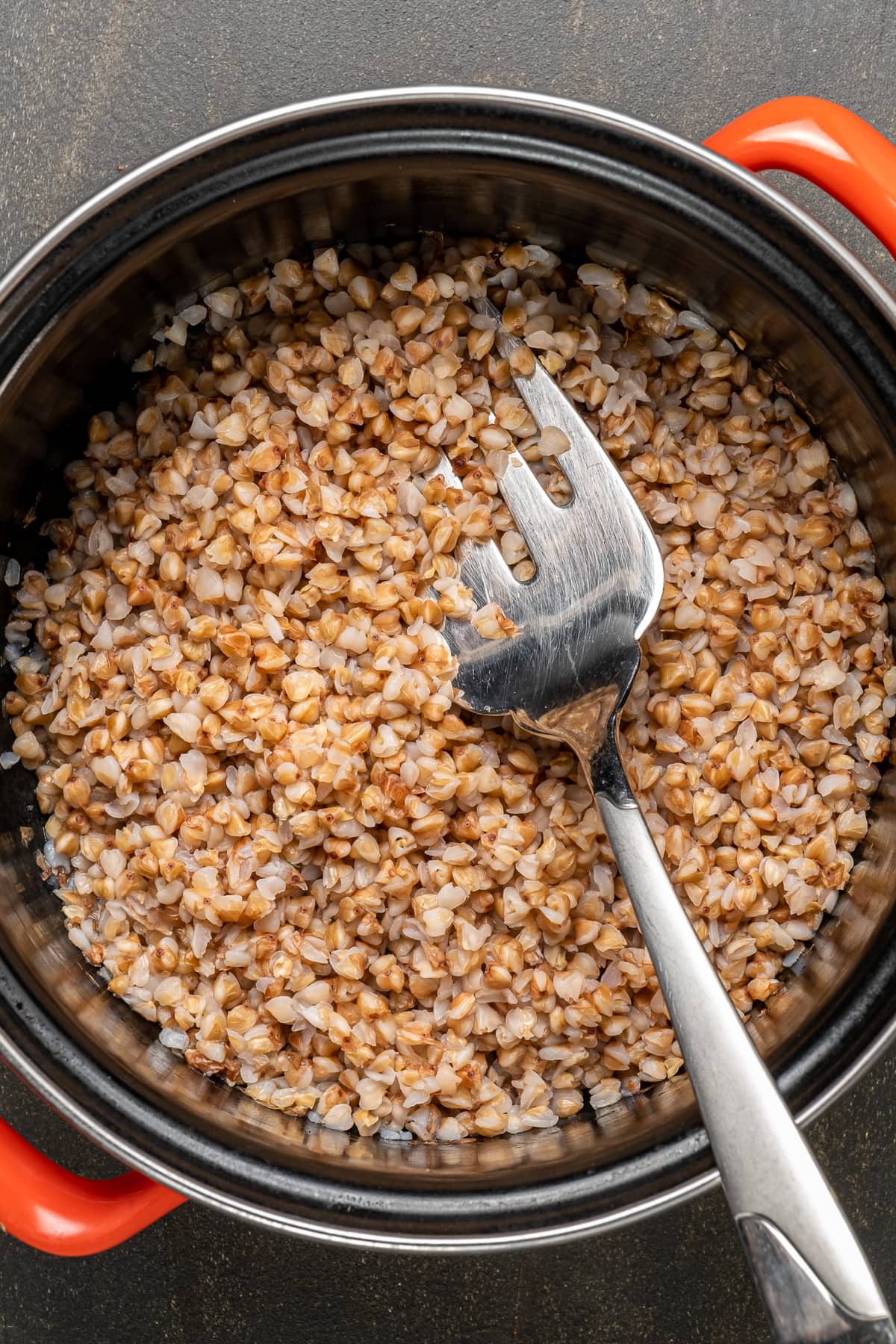 Cooked buckwheat in a pan and a fork inside it.
