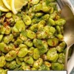 Fresh fava beans cooked in olive oil served in a bowl with lemon slices, dill, and red pepper flakes.