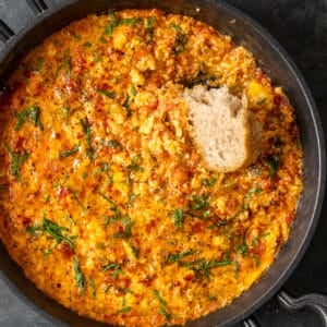 Menemen in a pan and a piece of bread in it.