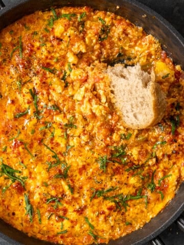 Menemen in a pan and a piece of bread in it.