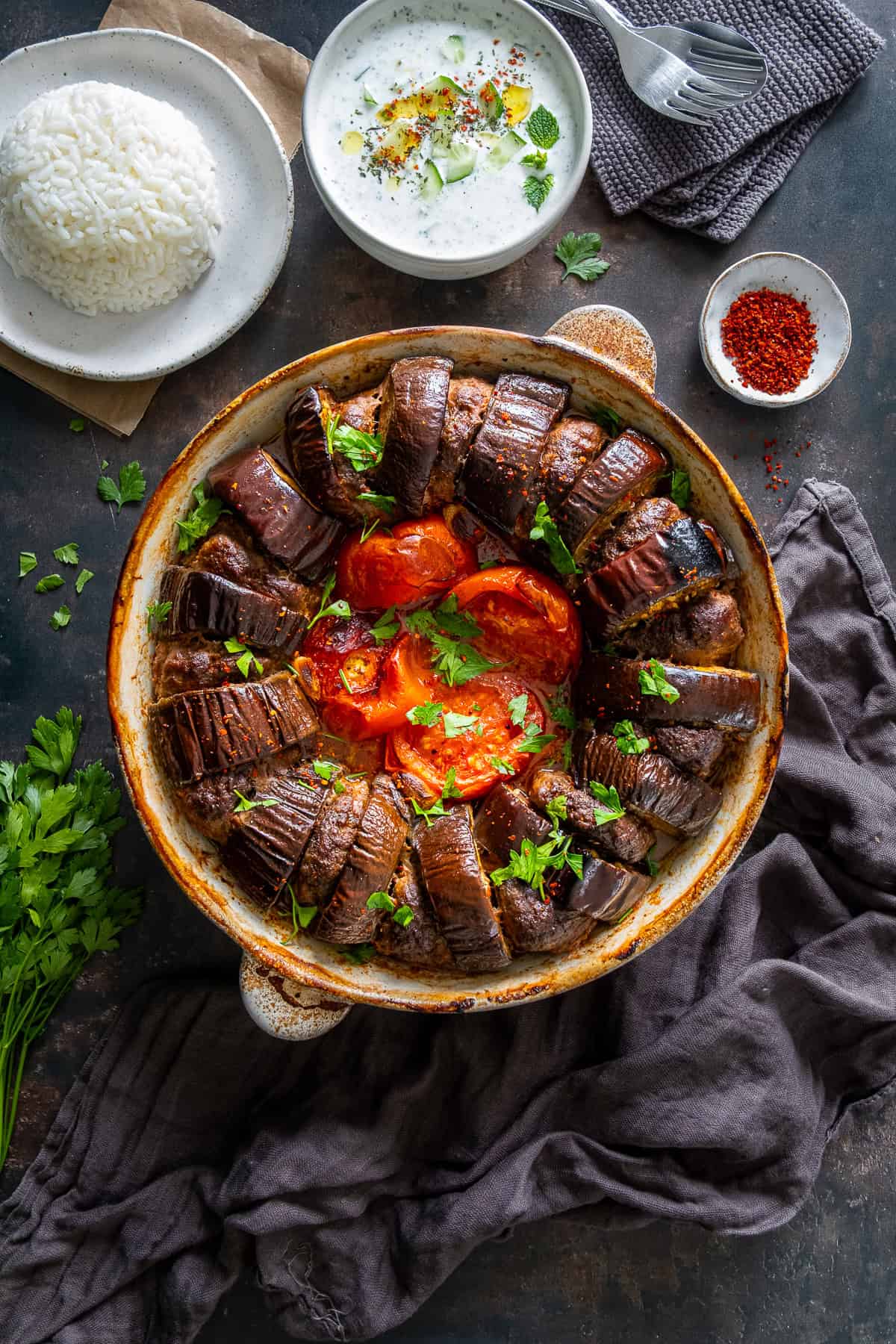 Turkish eggplant kebab served in a round baking dish with rice pilaf and cacık on the side.
