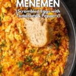 A piece of bread dipped into menemen in a pan.