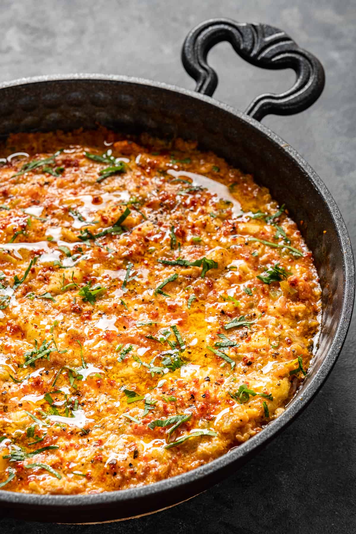 Menemen topped with parsley and pepper flakes in a pan.