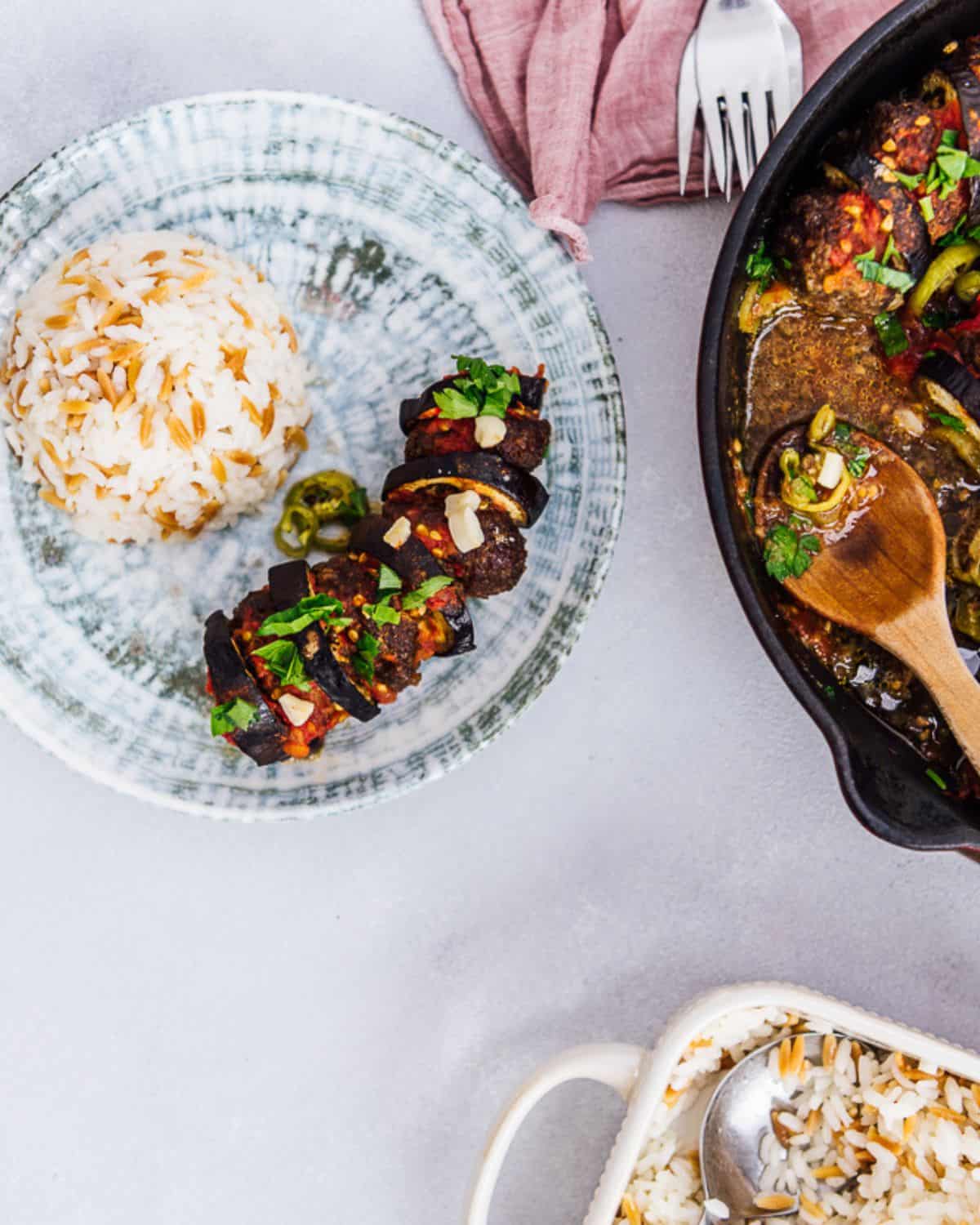 An image of eggplant kebab served with Turkish rice pilaf on a plate.