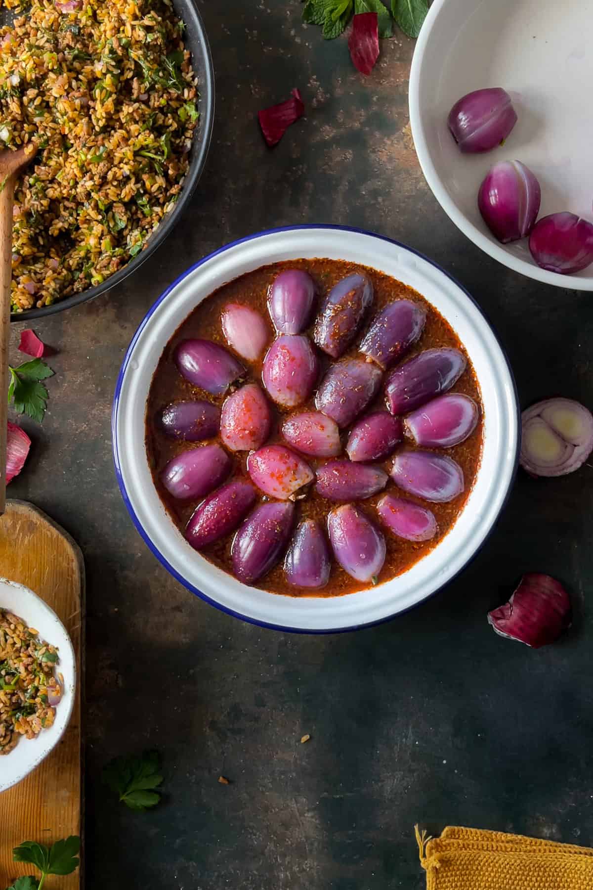 A baking dish filled with Sogan Dolmasi (Turkish Stuffed Onions) arranged in a circular pattern, ready to be cooked in a rich tomato-based sauce.