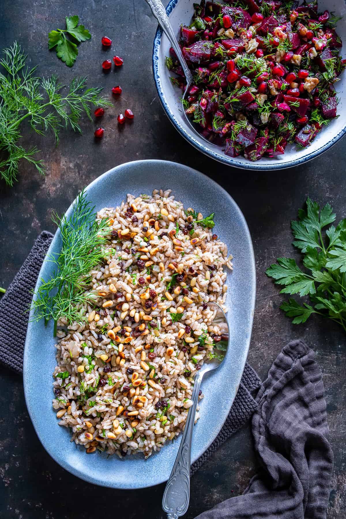 Turkish iç pilav served with toasted pine nuts and currants, photographed with fresh herbs and a side salad.