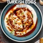 Turkish eggs served in a blue bowl with spicy butter sauce and chopped fresh dill on a dark background.