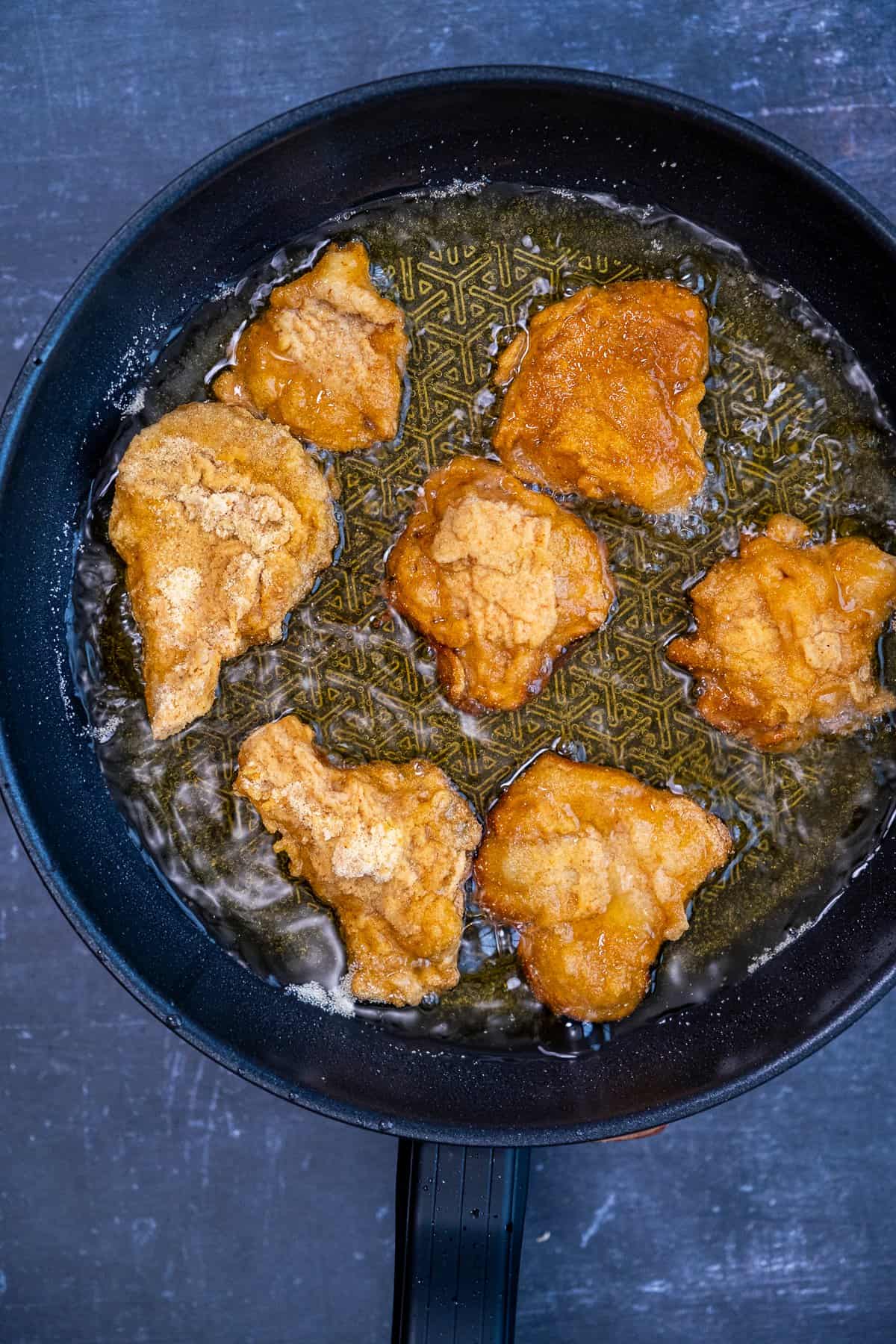 Breaded oyster mushrooms frying in hot oil in a pan.