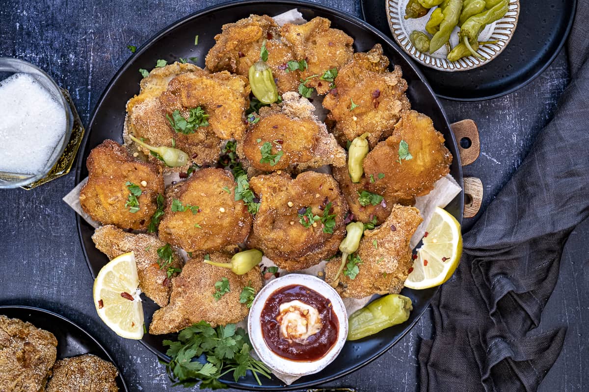 Oyster mushrooms fried and served with a dipping sauce, pickles, lemon wedges and a glass of beer on the side.