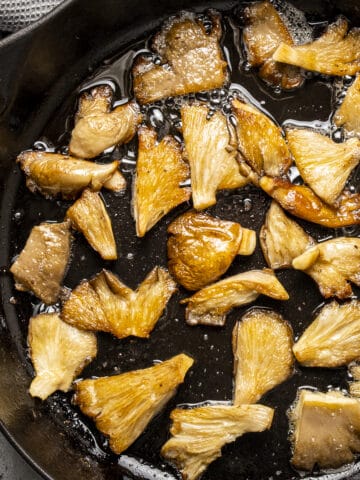 Golden oyster mushrooms sauteed in a cast iron pan.