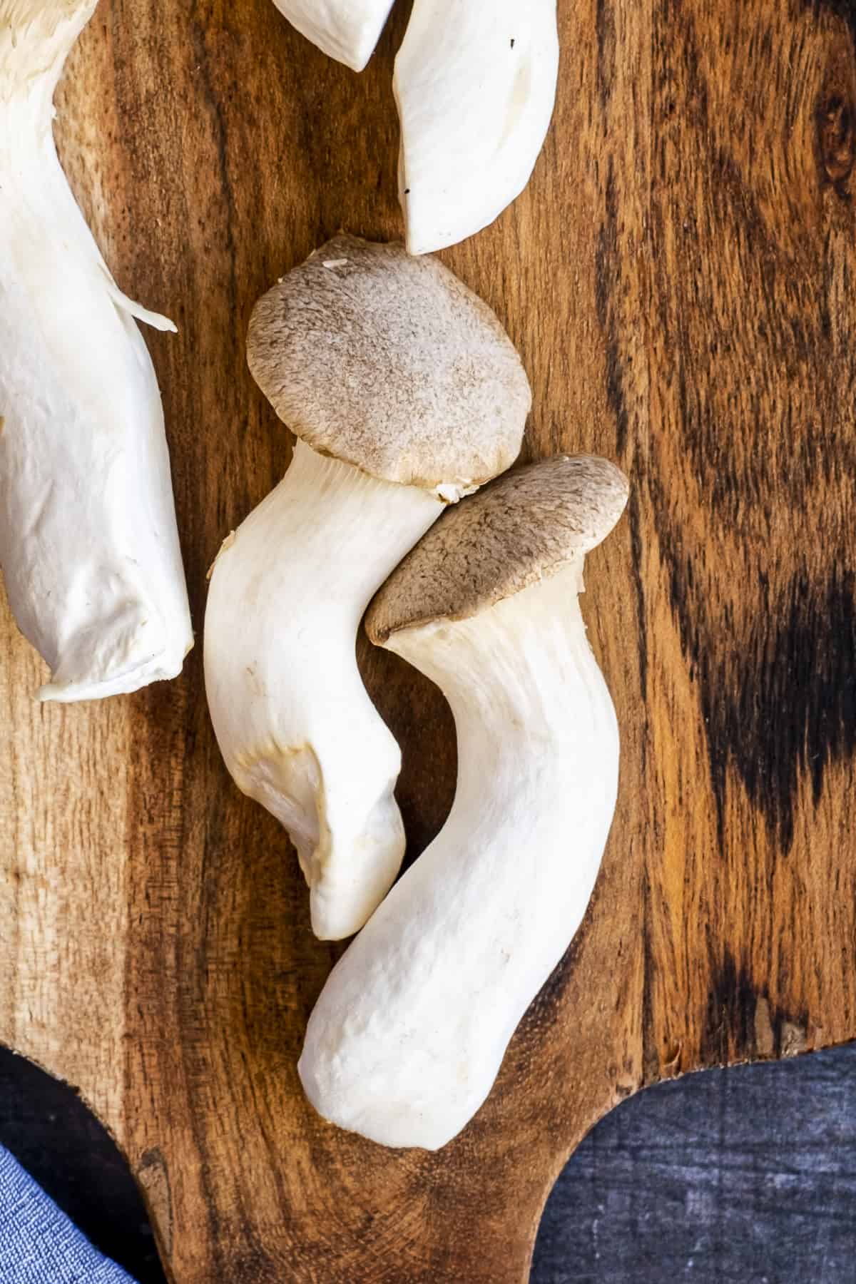 King oyster mushrooms on a wooden cutting board.